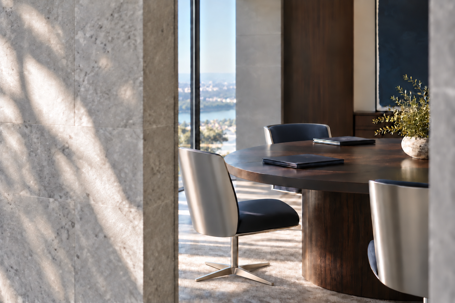 An architectural meeting-space detail with a dark timber table and sculptural seating in soft daylight